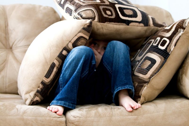 child hiding under the pillows